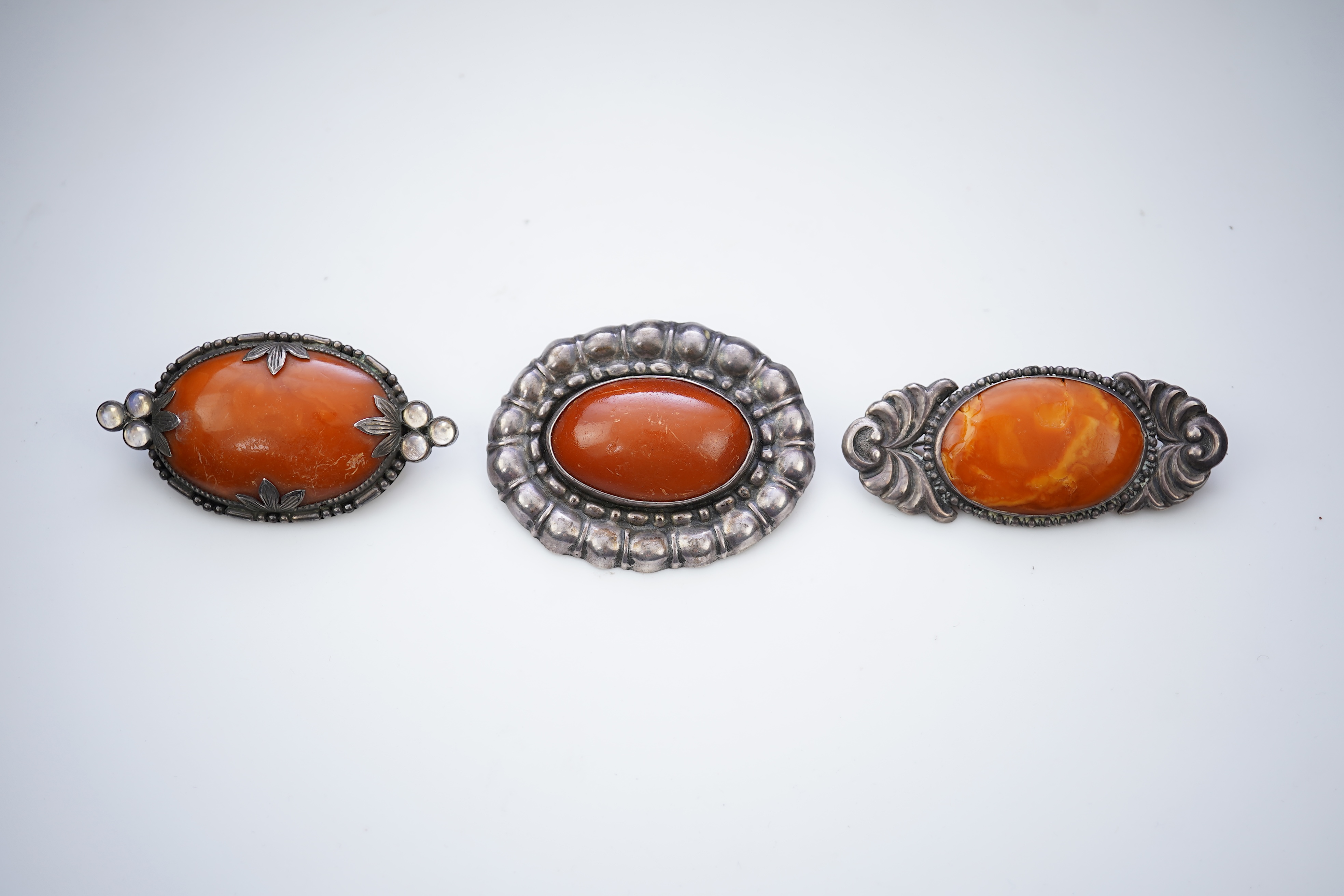 Three Arts & Crafts silver and amber brooches, early 20th century